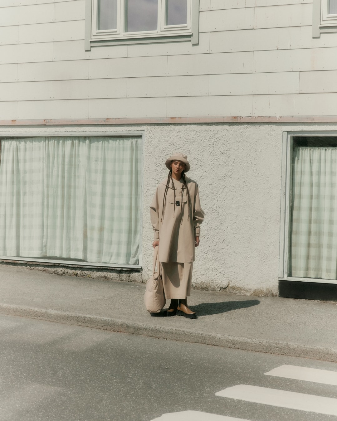 Woman pairing BLÆST's pillow bag and bucket hat with her Bergen poncho