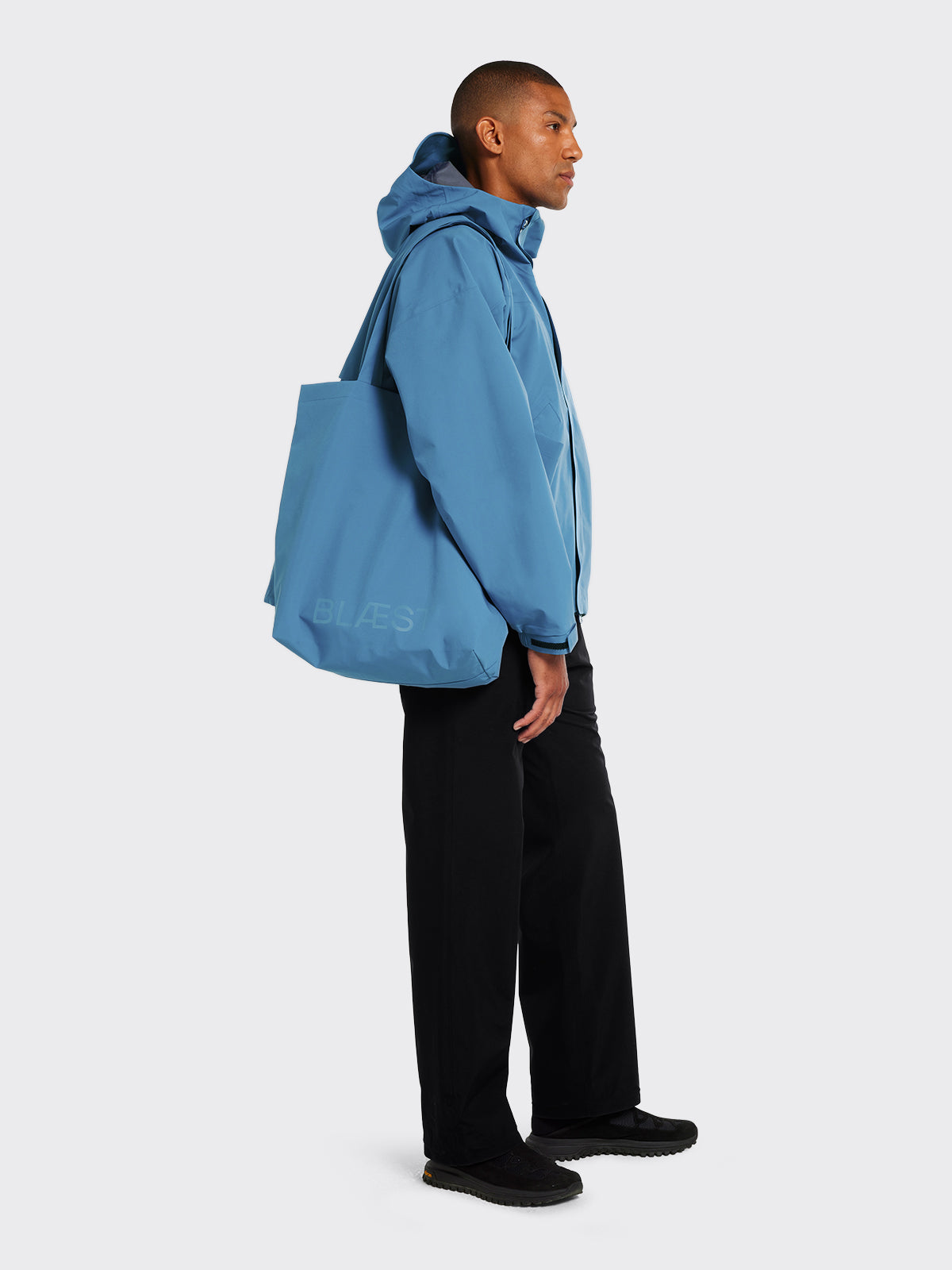 Man wearing Synes jacket and Moa tote bag by Blæst in Coronet Blue